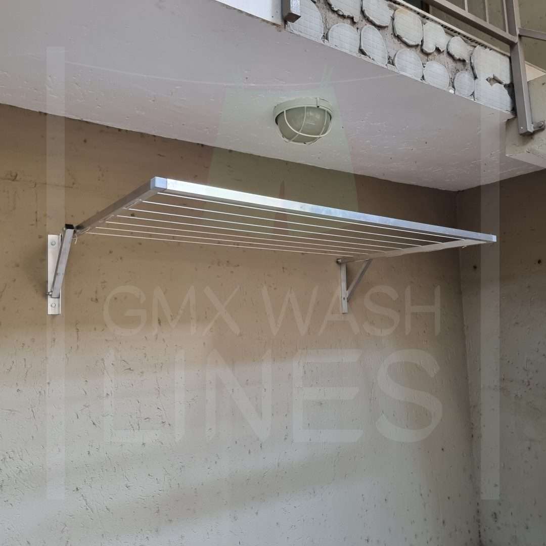 Aluminum foldable washing line extended against a white textured wall